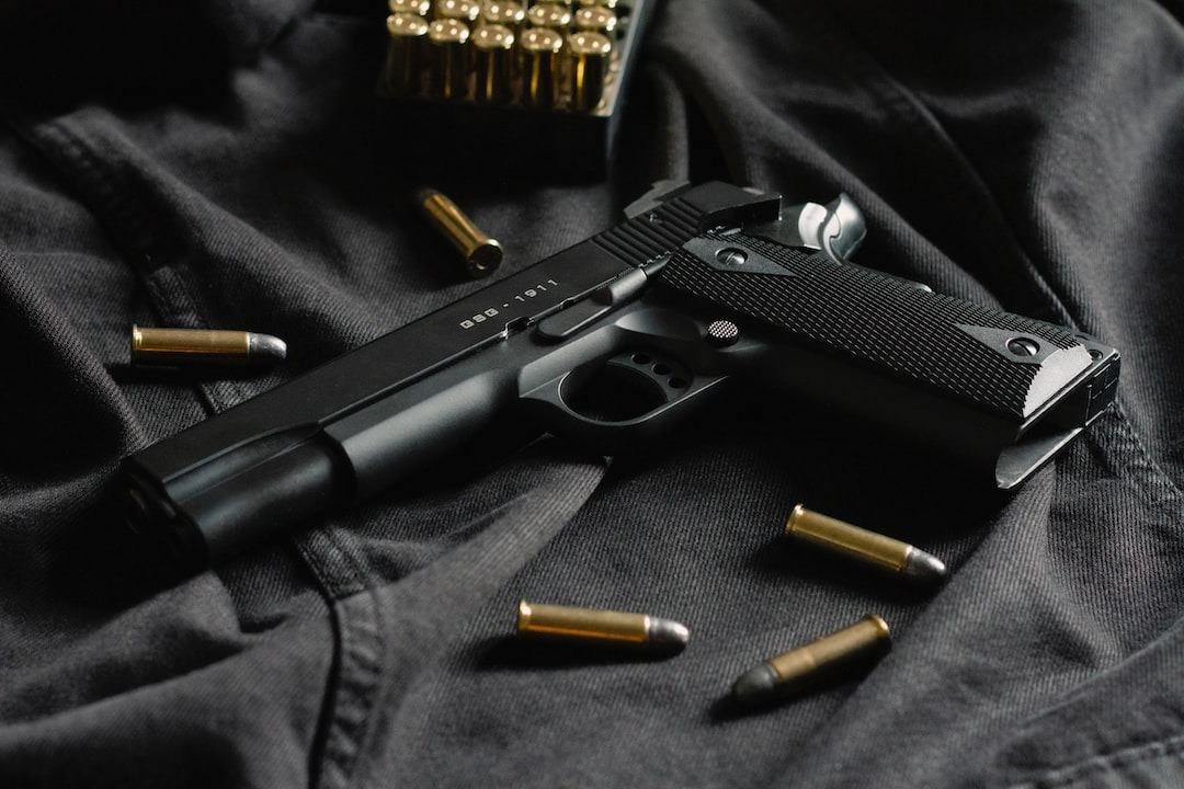 Black 1911 handgun with scattered pistol ammunition on dark fabric.